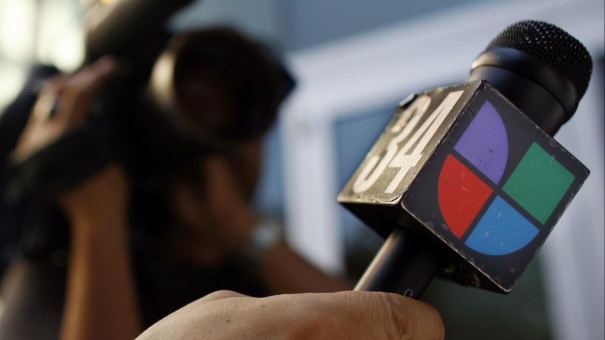 A journalist holds a microphone bearing the Univision logo in Los Angeles.