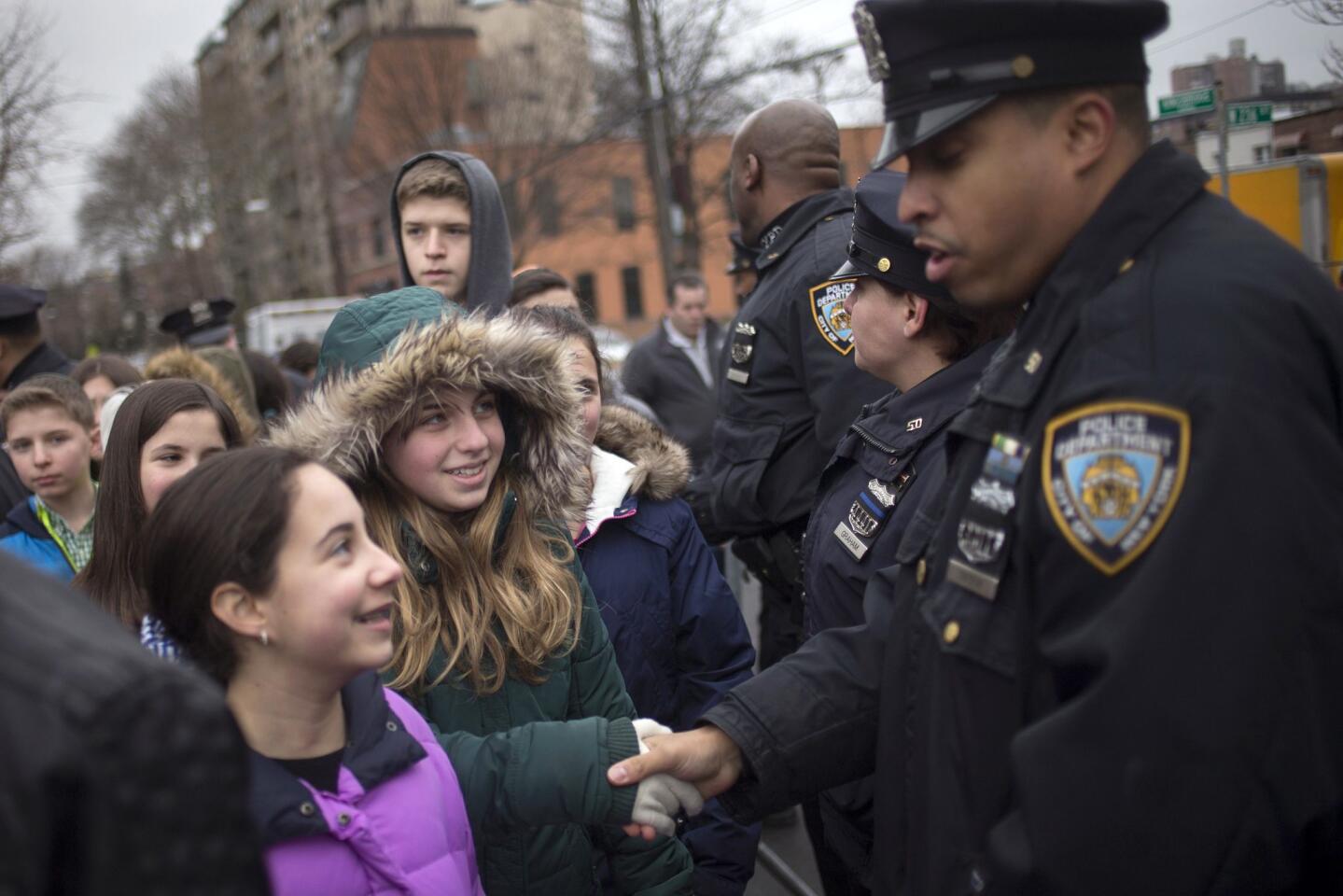 School children, who gathered with dozens to show support for policemen two days after officers Wenjian Liu and Rafael Ramos were shot and killed, meet with New York Police Department (NYPD) officers\