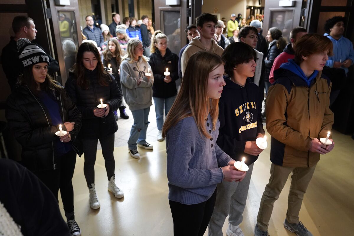 Students stand in a hall holding candles.