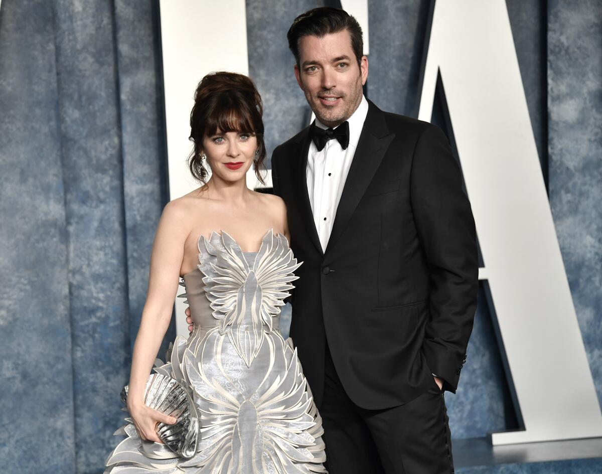 Zooey Deschanel poses in a strapless silver gown next to a tuxedo-clad Jonathan Scott