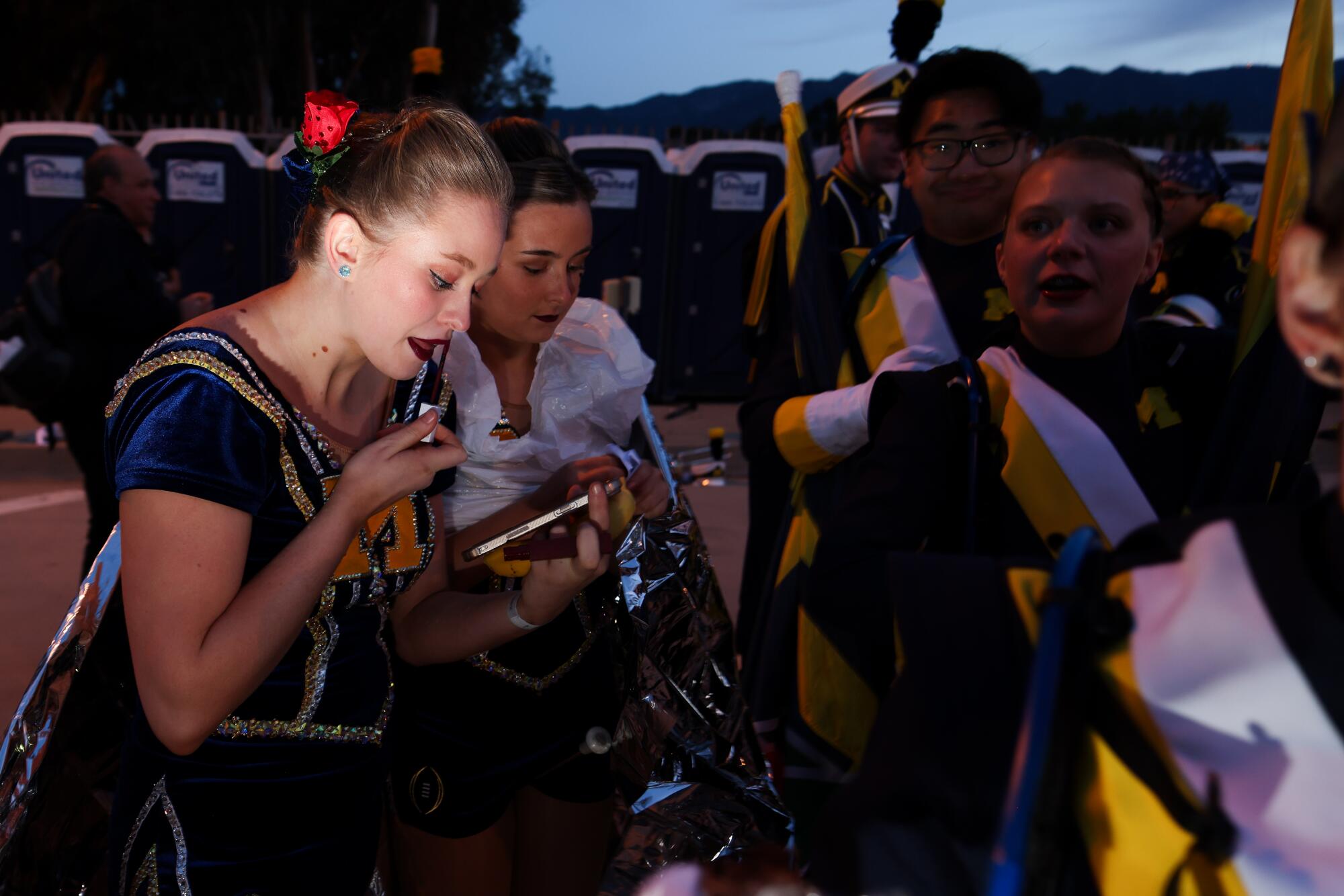 A Michigan Twirler puts on lipstick in the predawn darkness before the Rose Parade.