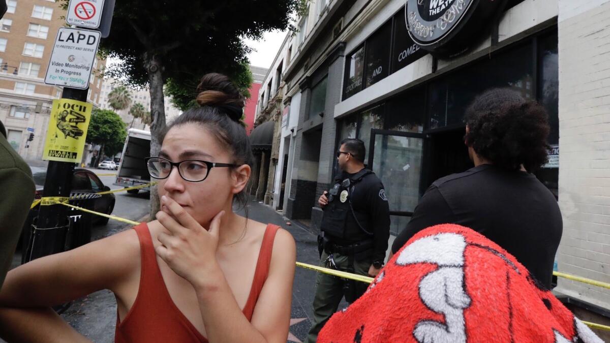 Jasmine Acosta stands outside a vacant commercial building in Hollywood, where more than 60 occupants were removed as the LAPD searched the building.