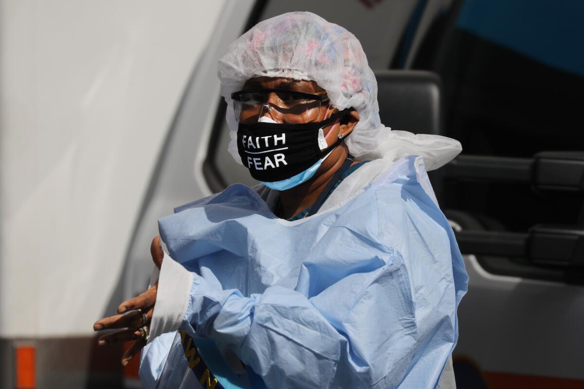A medical worker with 'faith over fear' on her mask pauses outside a coronavirus intake area at Maimonides Medical Center in Brooklyn on Thursday. 