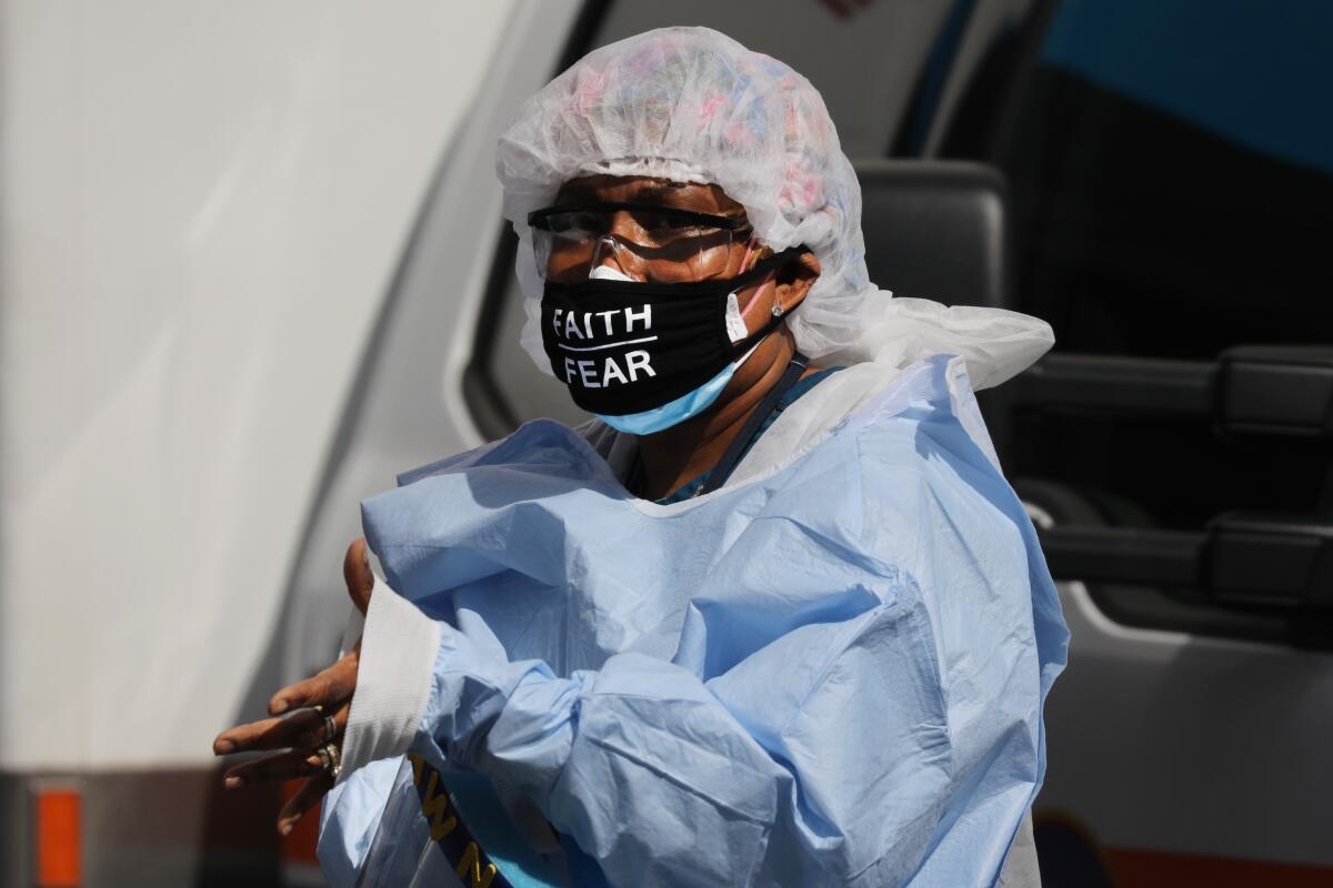 A medical worker with 'faith over fear' on her mask pauses outside a coronavirus intake area at Maimonides Medical Center in Brooklyn on Thursday.