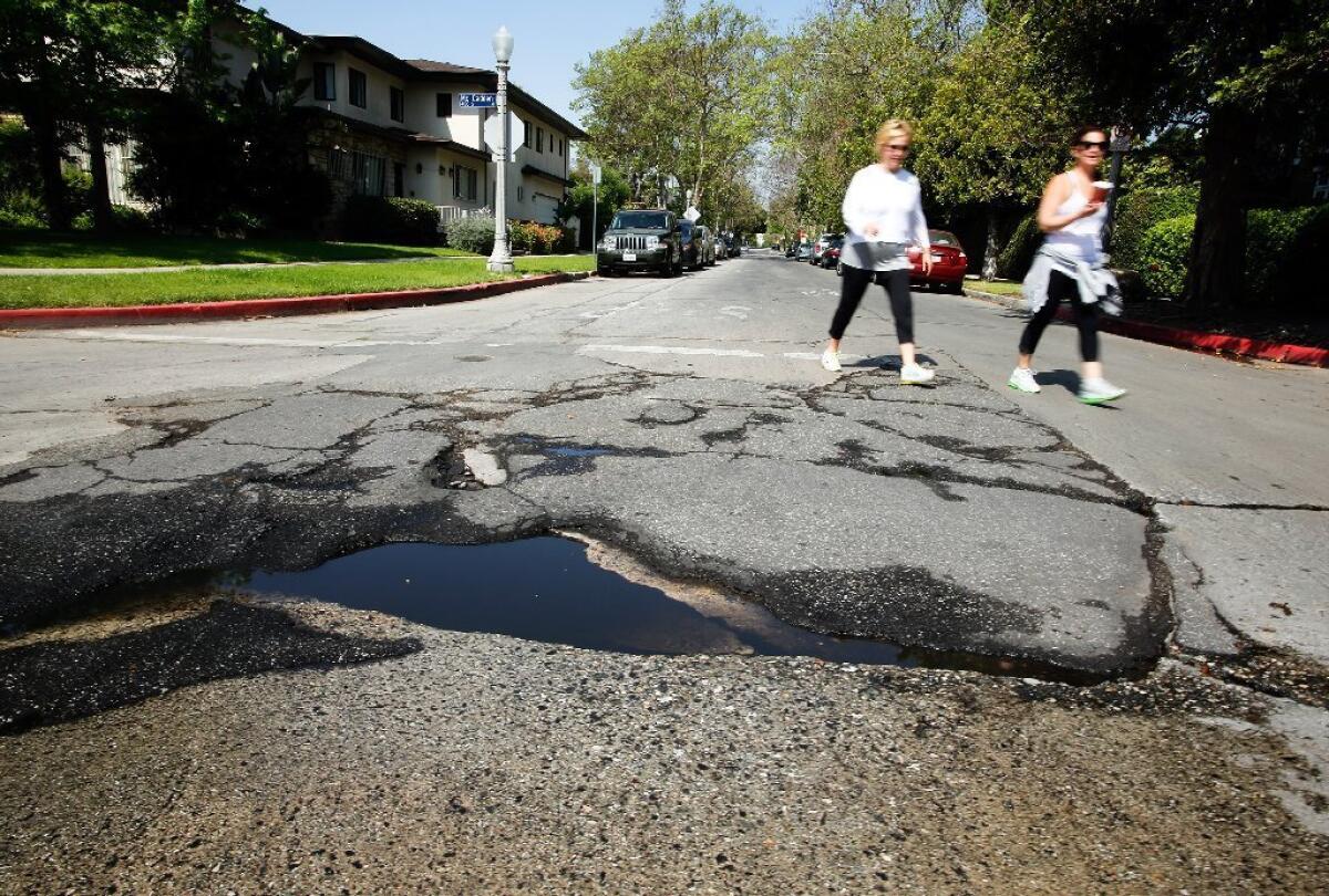 Women pass by a pothole at McCadden Place and 4th Street in Hancock Park. Los Angeles has a 60-year, $3-billion backlog of street repairs.