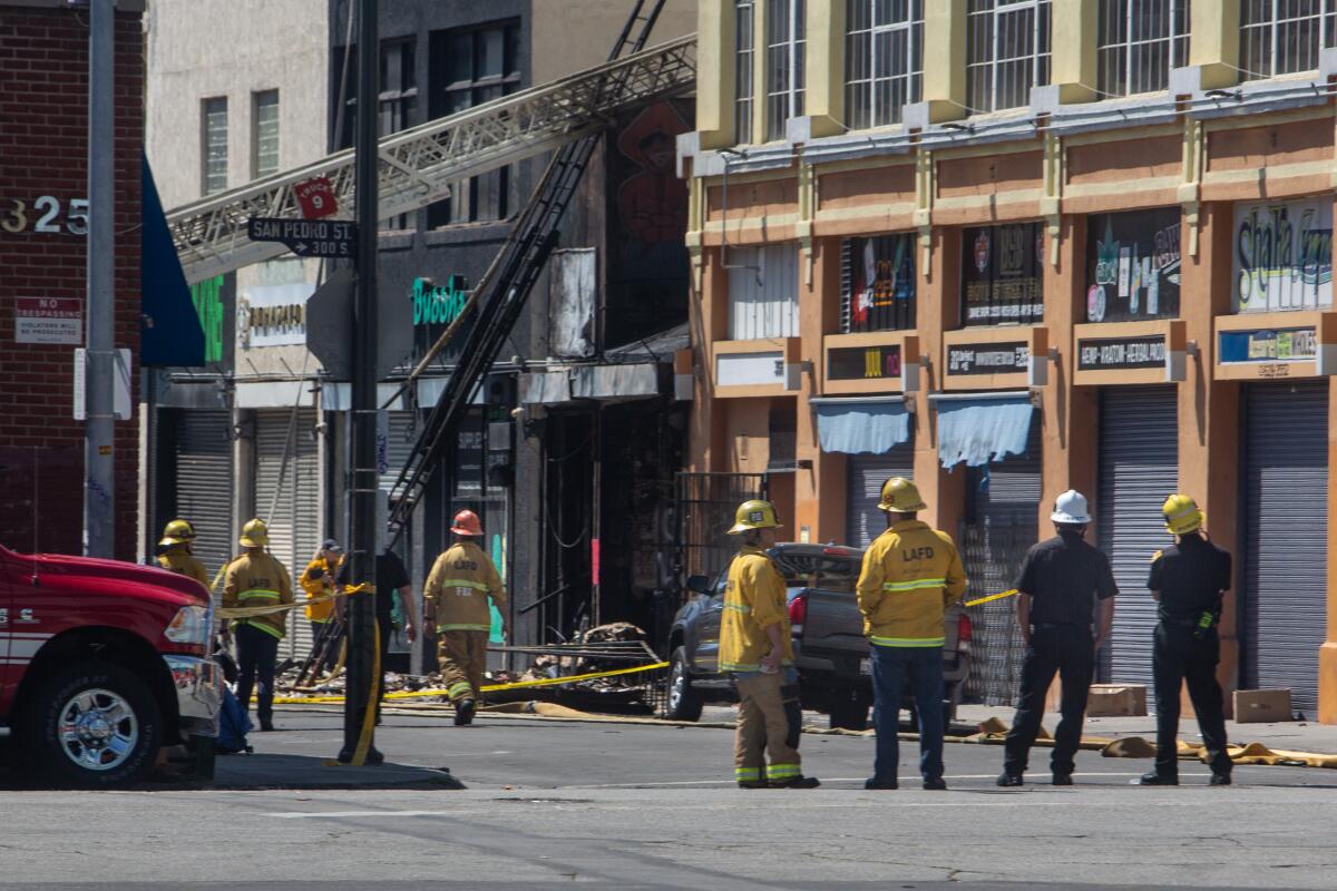 Firefighters and other officials investigate a downtown scene were an explosion and fire injured 11 fire fighters yesterday in Little Tokyo during the coronavirus pandemic on Sunday, May 17, 2020 in Los Angeles, CA.