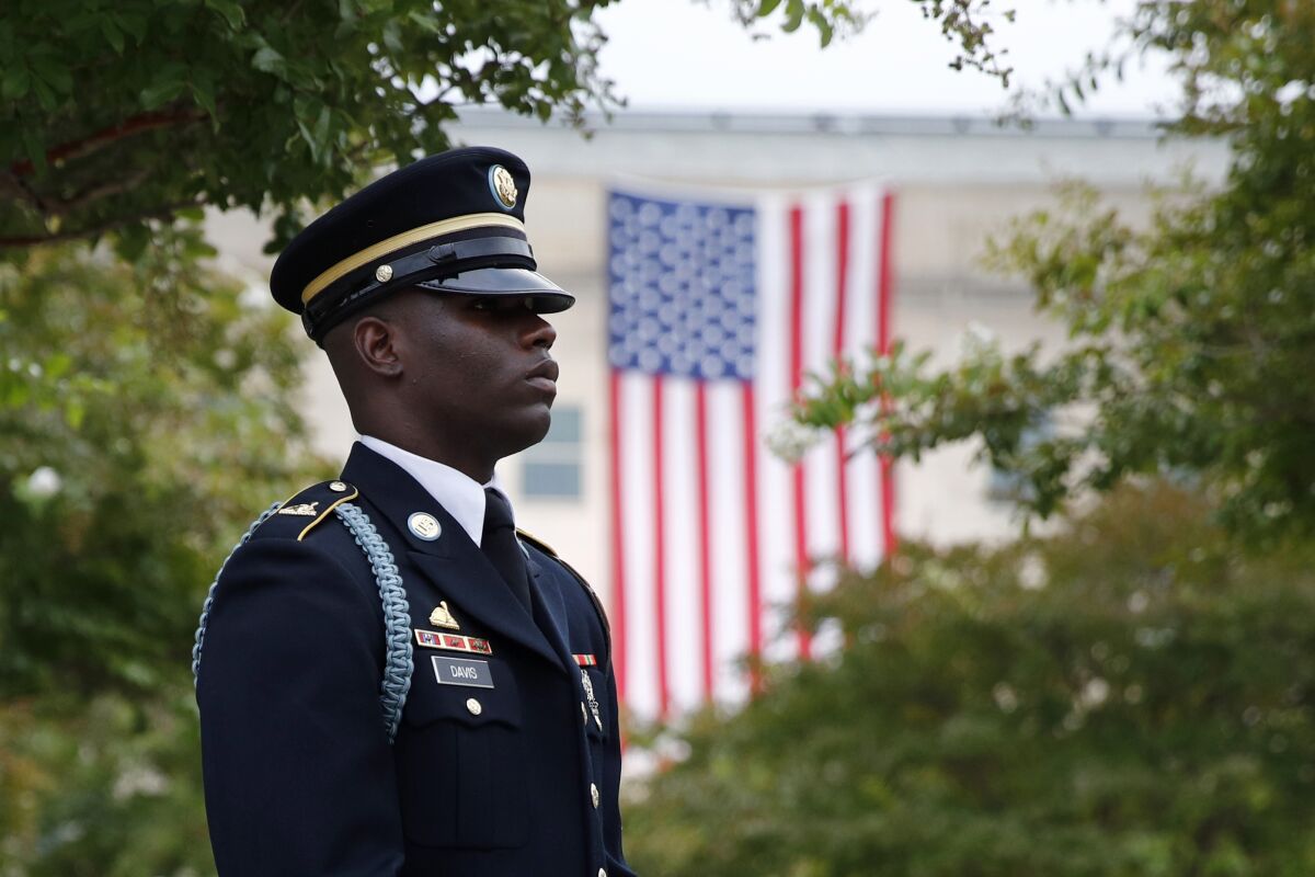 FILE - In this Sept. 11, 2019, file photo, a member of the U.S. Army Old Guard stands on the grounds of the National 9/11 Pentagon Memorial before a ceremony in observance of the 18th anniversary of the September 11th attacks at the Pentagon in Washington. On Sept. 11, 2020, Americans will commemorate 9/11 with tributes that have been altered by coronavirus precautions and woven into the presidential campaign. (AP Photo/Patrick Semansky, File)