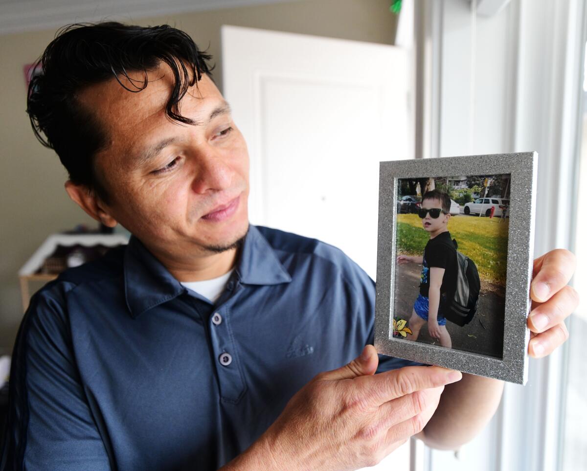 Carlos Rivera holds a photo of his son, Enrrique