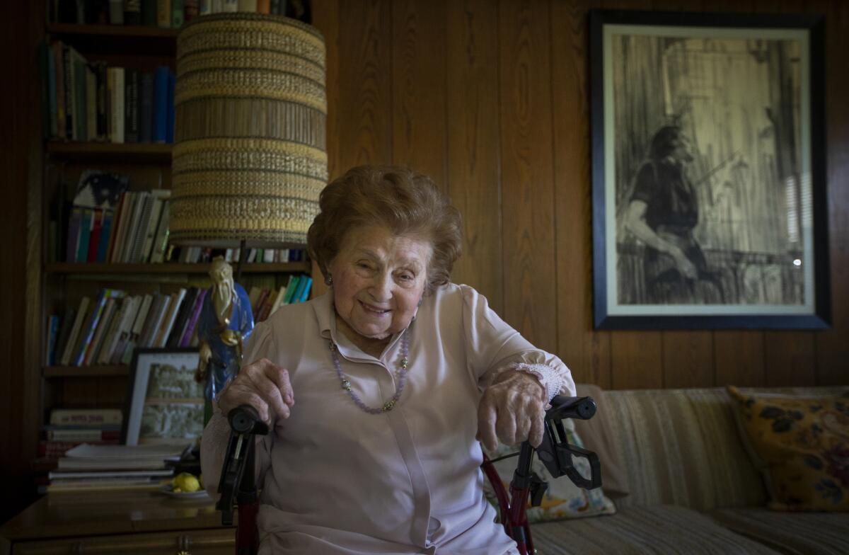 Pearl Berg smiles while sitting in a chair in her living room.