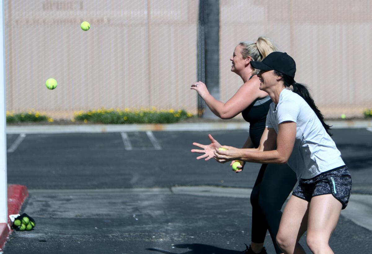 The Packaged Deal softball school owner Jen Schroeder, left, plays a game of catch with friend Morgan Stuart, right, on Tuesday.