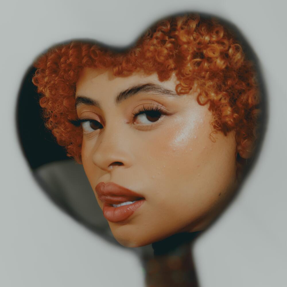 A close-up of a female rap star as reflected in a heart-shaped mirror 