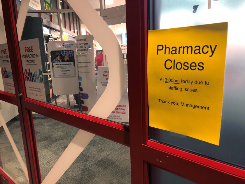 A sign is posted outside a CVS pharmacy on Thursday, Dec. 2, 2021 in Indianapolis. A rush of vaccine-seeking customers and staff shortages are squeezing drugstores around the country. That has led to frazzled workers and even temporary pharmacy closures. (AP Photo/Tom Murphy)