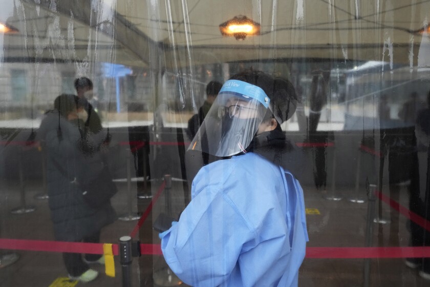 A medical worker guides people as they wait for their coronavirus test at a makeshift testing site in Seoul, South Korea, Thursday, Dec 16, 2021. (AP Photo/Ahn Young-joon)
