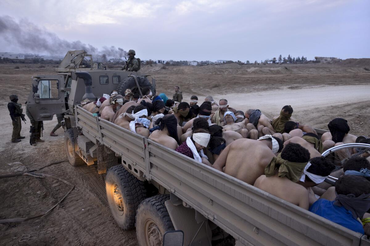 ARCHIVO - Soldados israelíes vigilan un camión con detenidos palestinos atados y con los ojos vendados en Gaza