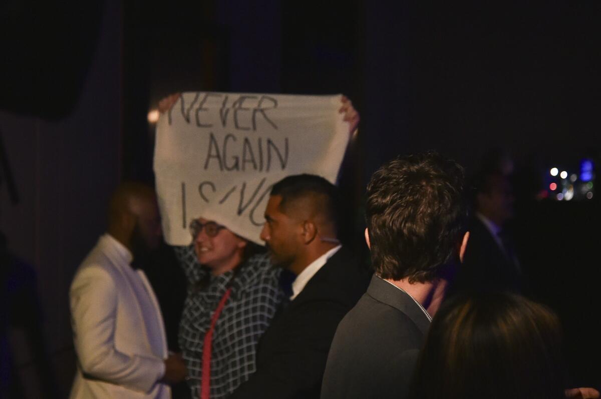 A protester holds a sign reading "Never Again."