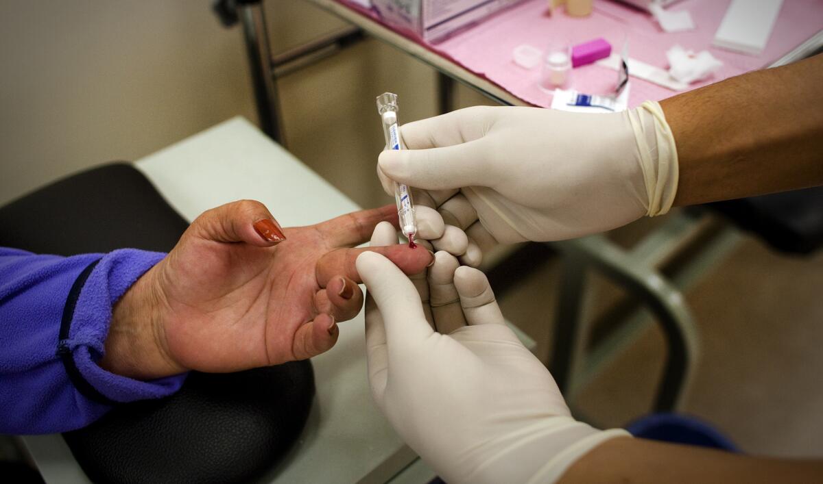 Medical assistant Hector Reyes administers an HIV blood test to patient Sara Guillen, 59, of Los Angeles at St. John's Well Child and Family Center on March 18, 2014, in Los Angeles.