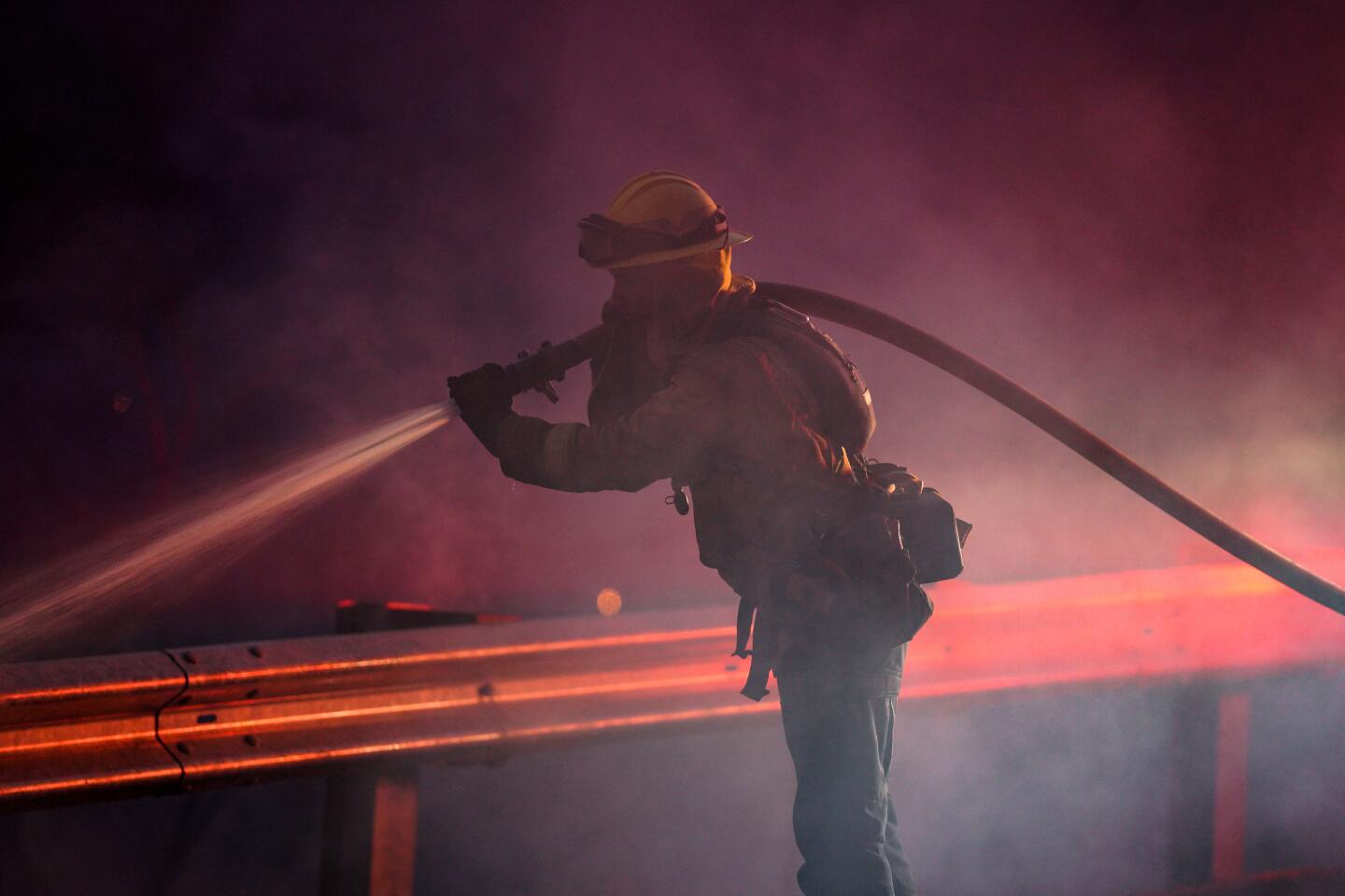 A firefighter sprays a hose over a railing.