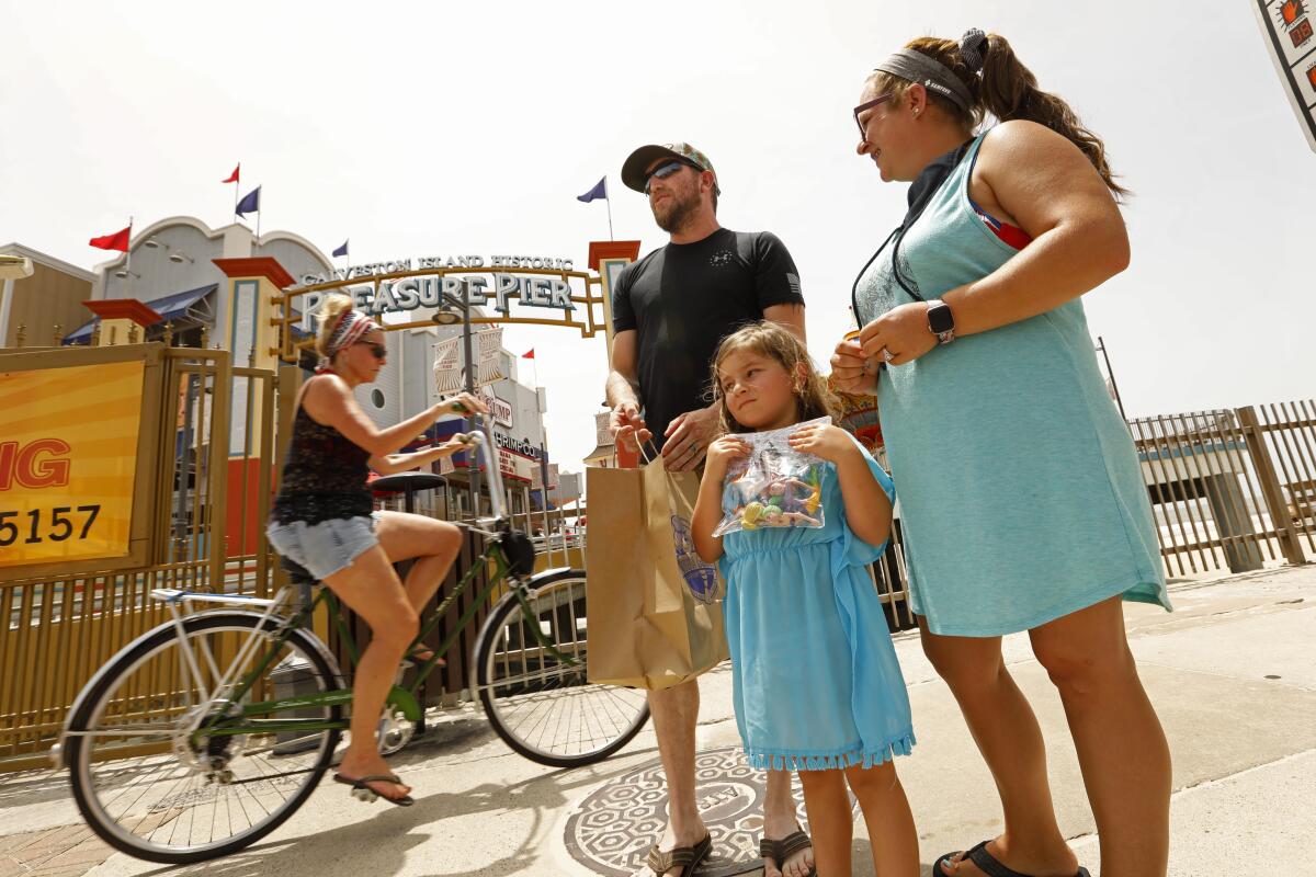 Jimmy, center, and Rachel Kinder, right, brought their daughter Arabella, 5, to the Pleasure Pier on Galveston Island.