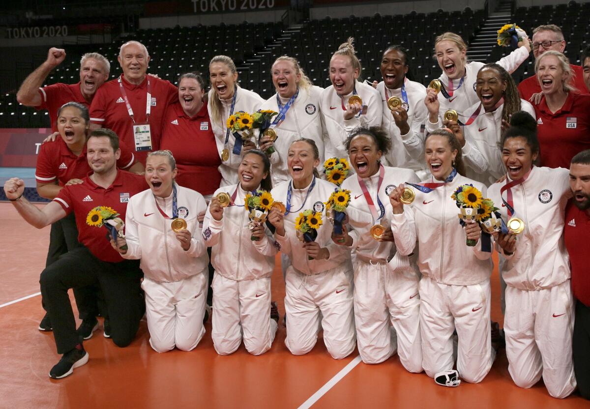 The U.S. women's volleyball team and staff gather with medals for a photo.