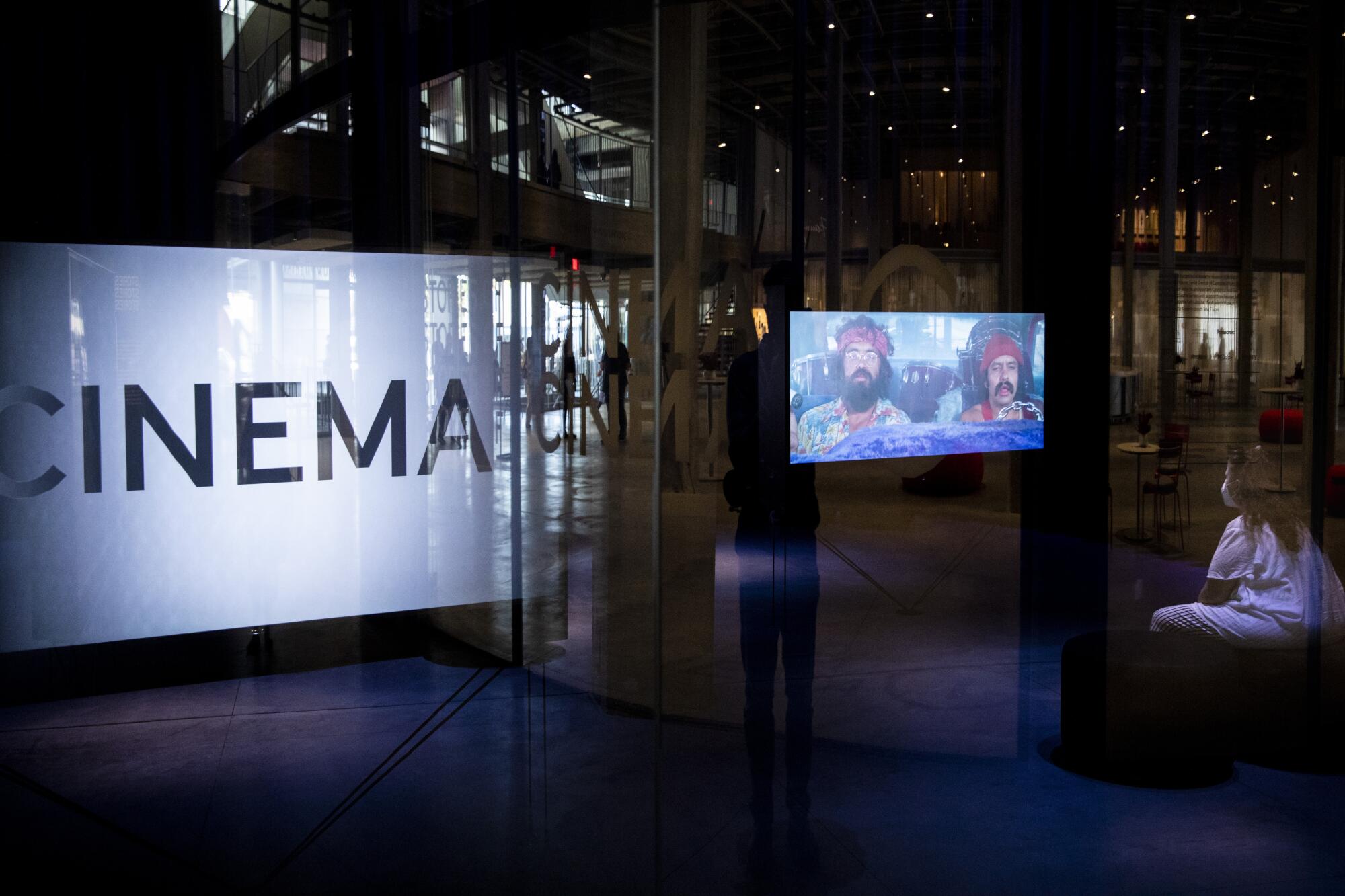 A visitor watches a scene from a Cheech and Chong film, inside the Spielberg Family Gallery.