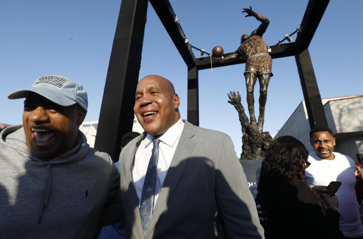Former Loyola Marymount star Bo Kimble, second from left, and ex-Clipper Pooh Richardson, left, celebrate the school's unveiling of a Hank Gathers statue Feb. 29, 2020.