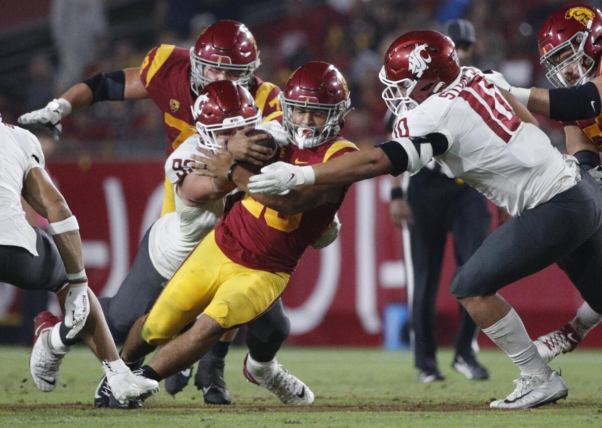 USC running back Travis Dye pushes through a tackle attempt by Washington State's Andrew Edson and Ron Stone Jr. 
