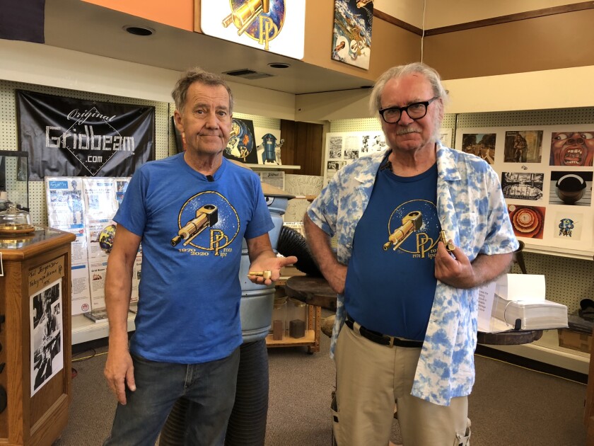 Two men holding brass smoking pipes