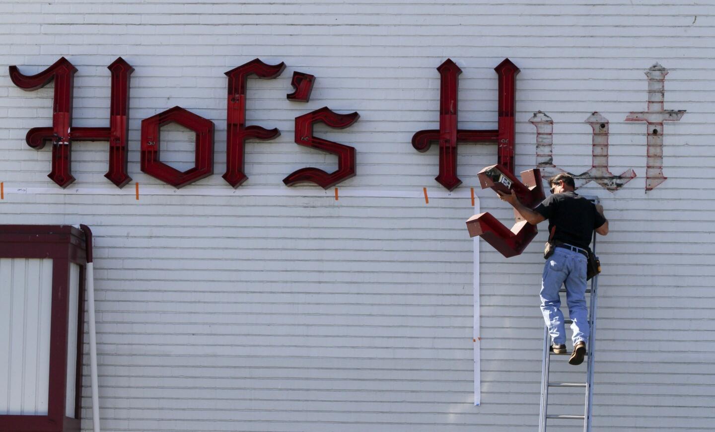 Mike Ciccarelli with ATC Signs starts removing the neon sign at Hof's Hut in the Long Beach Marina as the beloved coffee shop closes. Long known by locals for its comfort food and amazing pies, Hof's is being squeezed out by a strip mall that is being remodeled and gentrified.