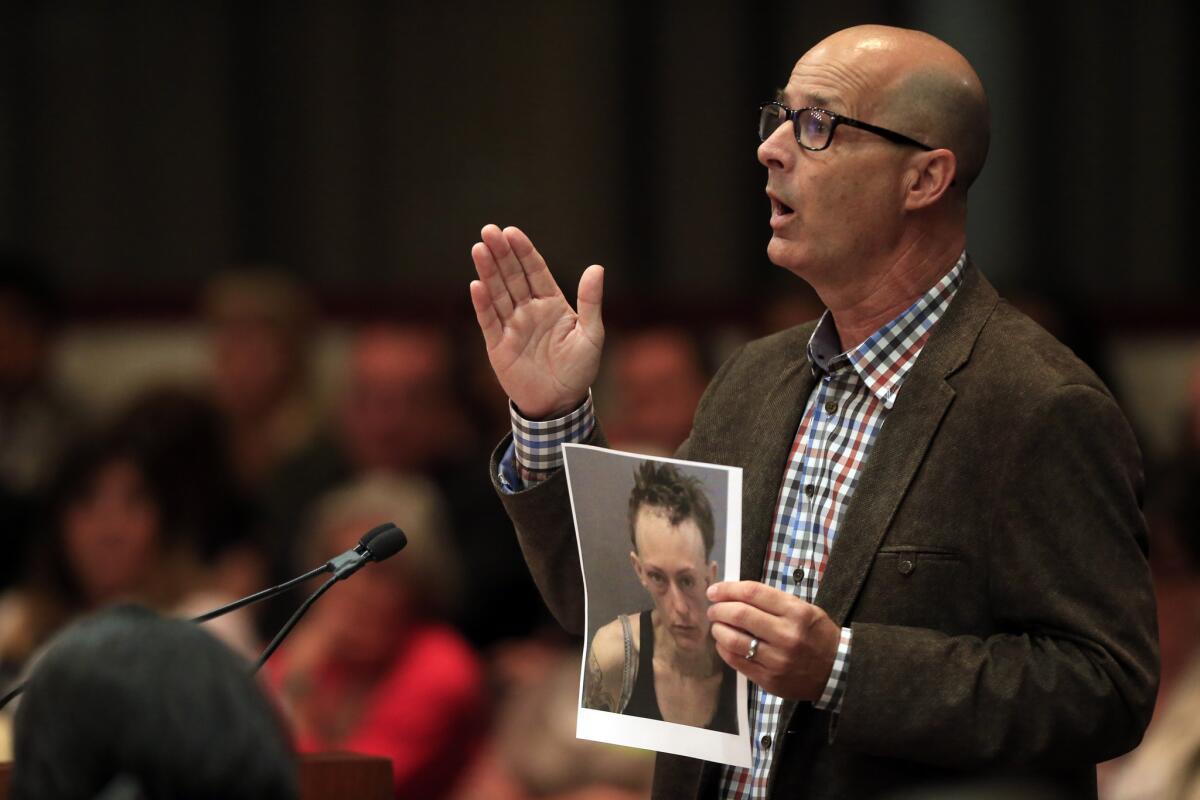 Michael Sitton holds a photo of his 31-year-old daughter, Tiffany who he says is mentally ill, while he addresses the Orange County Board Of Supervisors prior to their vote to implement Laura's Law last week. Laura's Law allows court-ordered treatment of mentally ill adults.