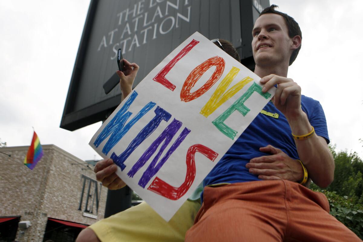 Daniel Hicks sits on a pillar in Atlanta with his boyfriend to watch the local crowd celebrate the U.S. Supreme Court's rulings on two landmark gay rights cases surrounding same-sex marriage.