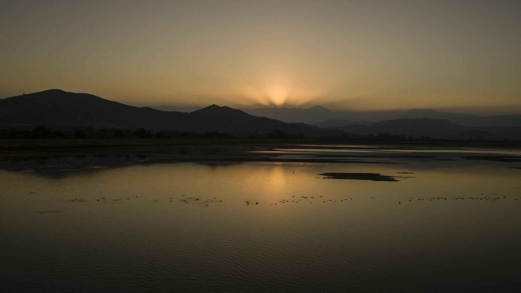 A body of water, with hills and mountains in the background.