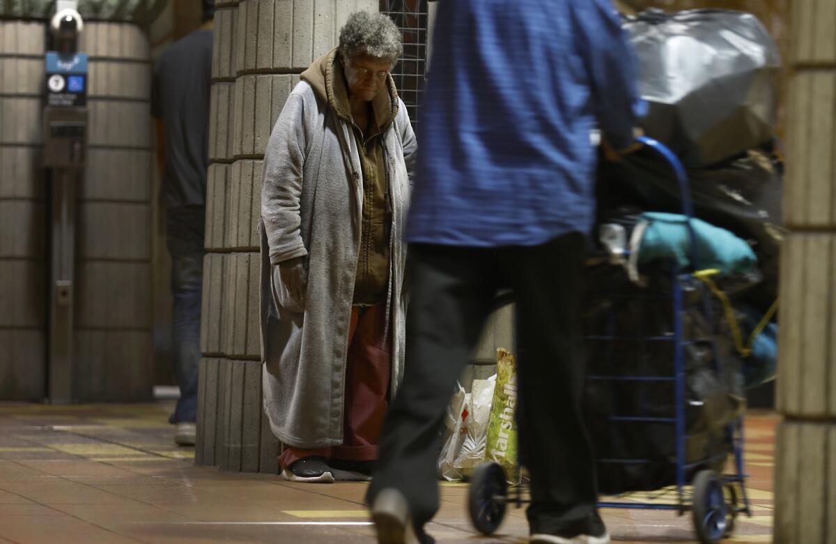 A homeless woman stands and watches as other pass by in the Hollywood/Vine Metro station in Los Angeles. (Francine Orr / Los Angeles Times)