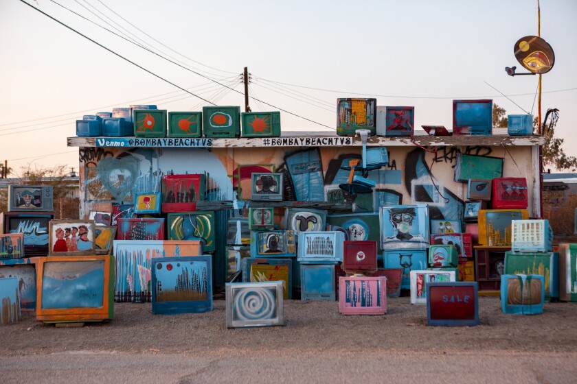 Try This Valentine's Day Road Trip In The California Desert - Los Angeles Times 5 TVs are stacked on and around a small brightly painted building. Their screens are covered in bright, swirling colors.