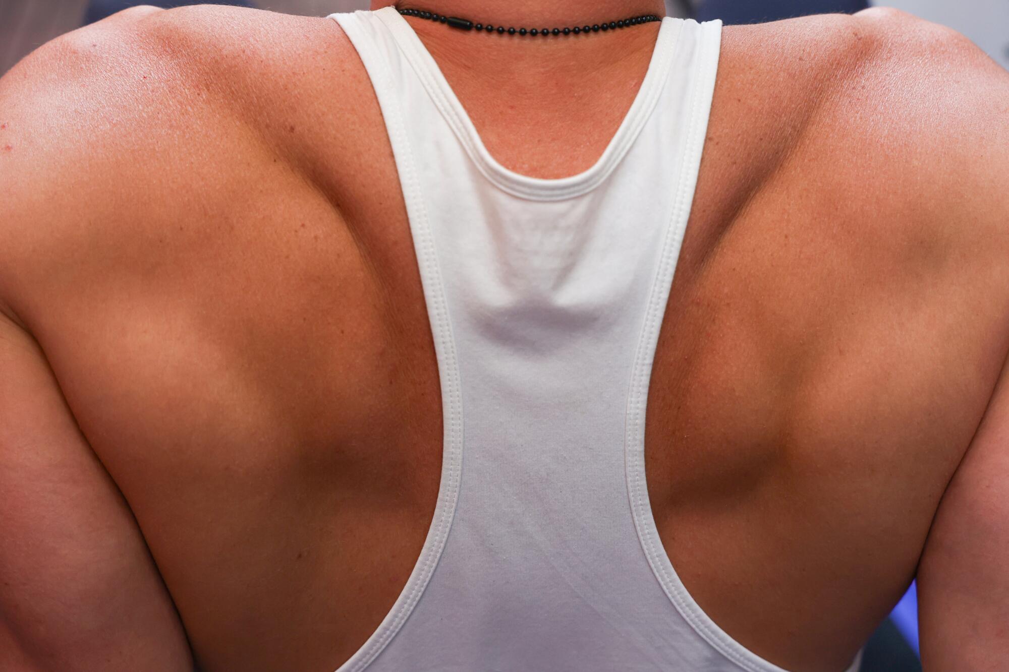 The back and shoulders of a person in a white tank top