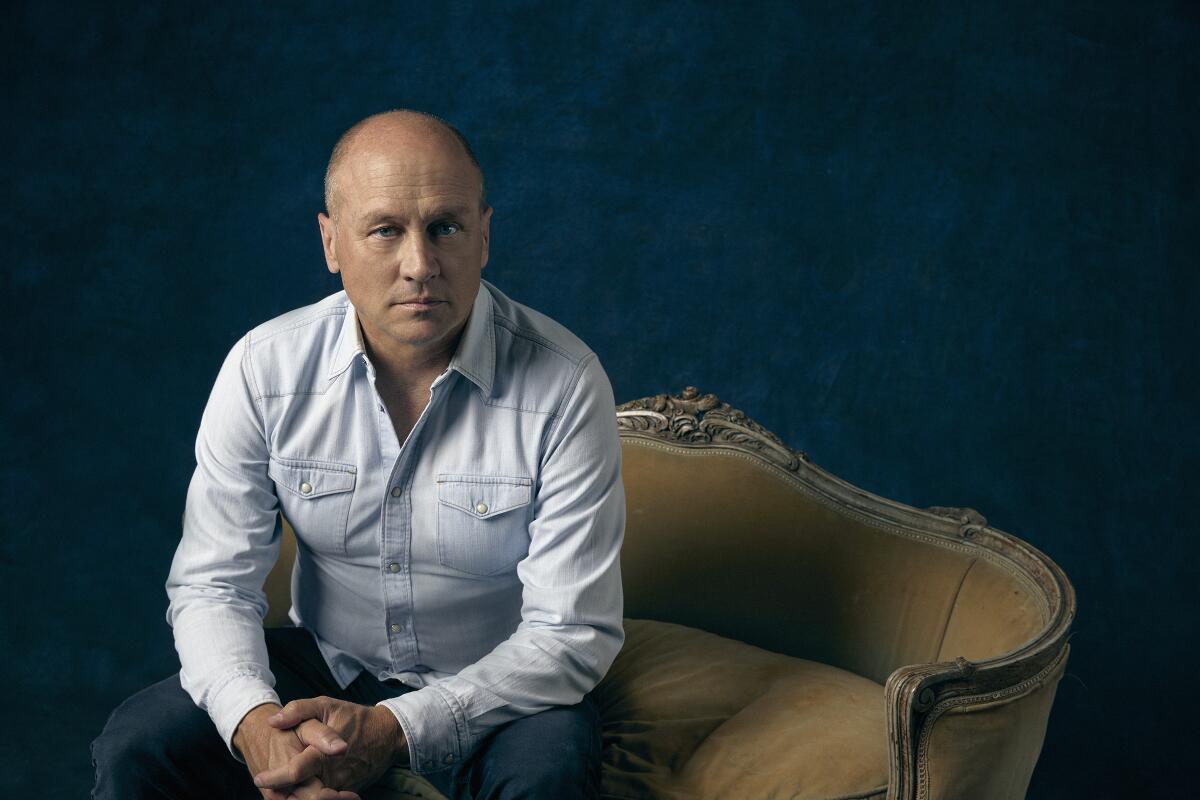 A man in a dress shirt sitting on a fancy yellow couch