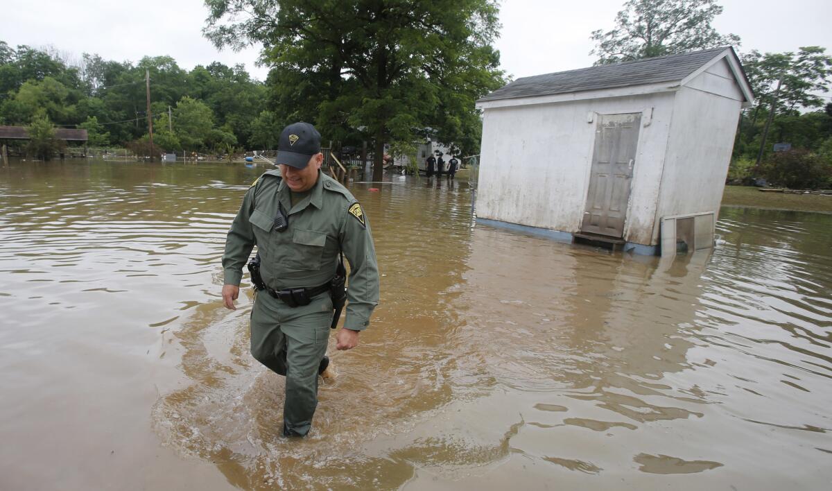 El patrullero estatal de West Virginia C.S. Hartman camina desde un cobertizo que comprobó mientras él y otras personas registran viviendas en Rainelle, West Virginia., el sábado 25 de junio de 2016. (AP Foto/Steve Helber)