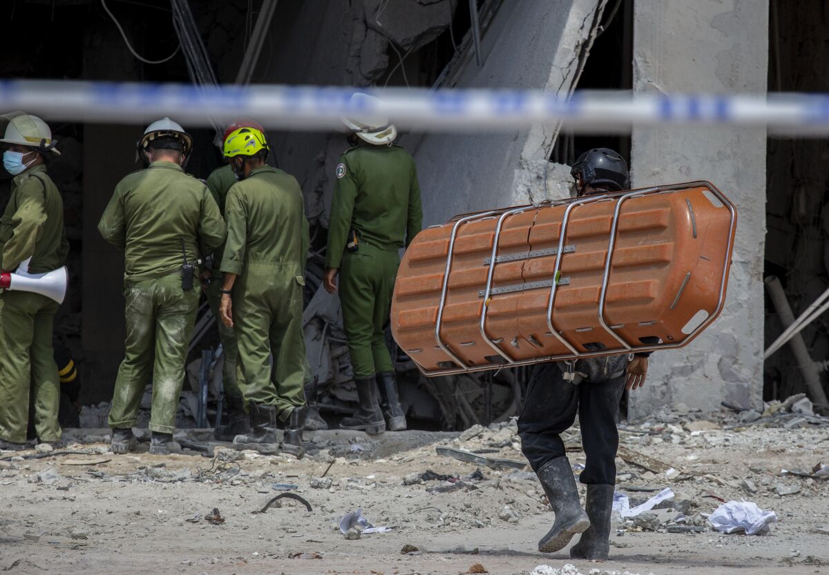 A member of the rescue team carries a stretcher to transport the body of a deceased person found in the rubble after a deadly explosion that destroyed the five-star Hotel Saratoga in Old Havana, Cuba, Sunday, May 8, 2022. (AP Photo/Ismael Francisco)