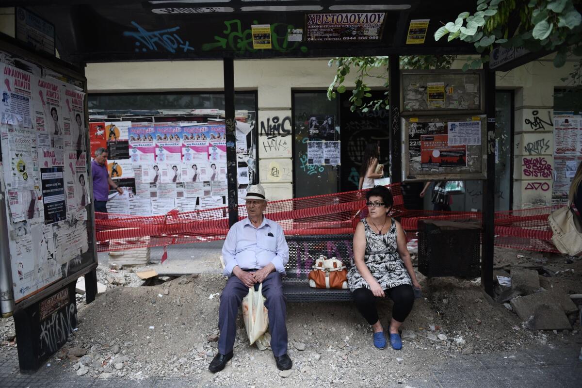 People wait for a bus in the northern Greek port city of Thessaloniki on June 30. Greek Finance Minister Yanis Varoufakis confirmed that the country would not be able to make a payment that is due the International Monetary Fund on Tuesday night.