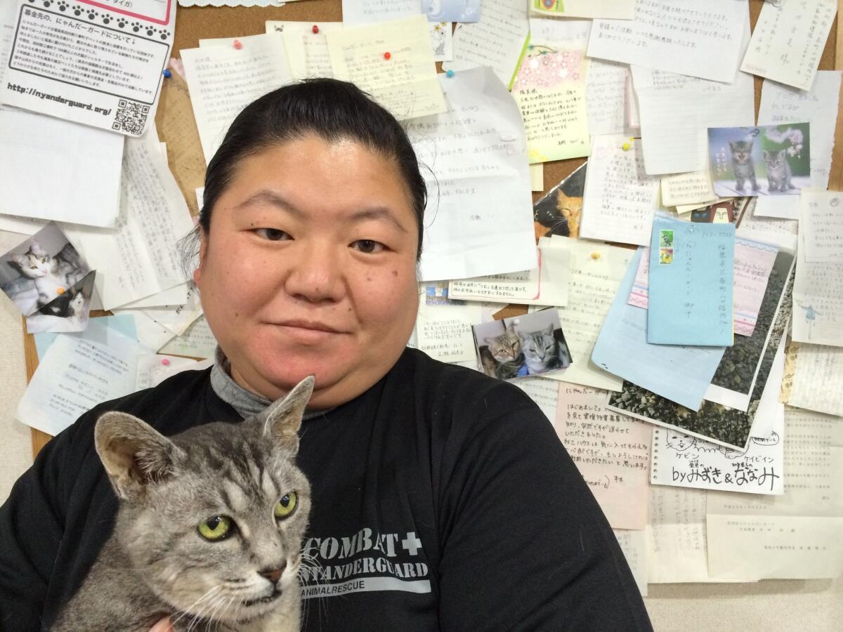 Takemi Shirota, an employee at the Nyander Guard animal shelter in Japan's Fukushima prefecture, holds a 20-year-old rescue cat named Kevin Costner.