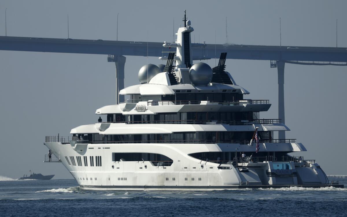 A massive yacht sails with a bridge in the background
