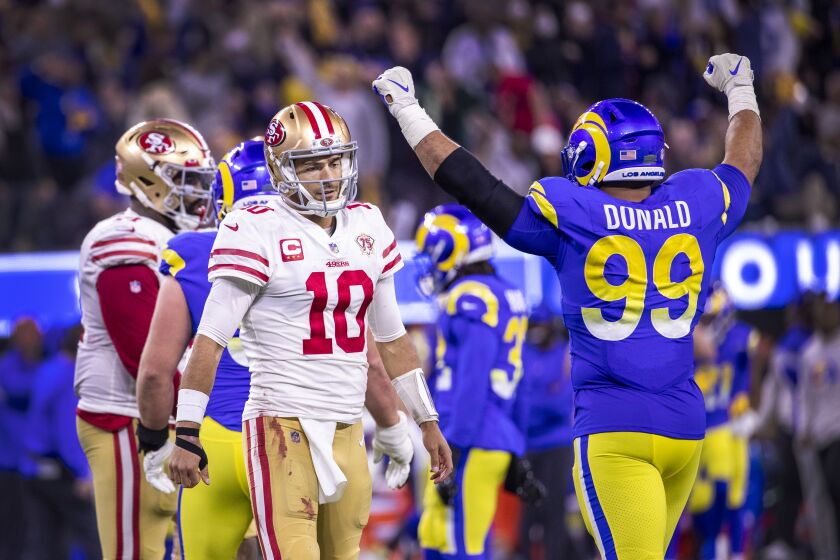 Los Angeles, CA - January 30: Rams defensive lineman Aaron Donald, right, celebrates as 49ers quarterback Jimmy Garappolo, left, walks away dejected after he failed to complete a pass for a first down, forcing a punt. The Rams celebrated their 20-17 victory over the San Francisco 49ers in the NFC Championships at SoFi Stadium on Sunday, Jan. 30, 2022 in Los Angeles, CA. (Allen J. Schaben / Los Angeles Times)