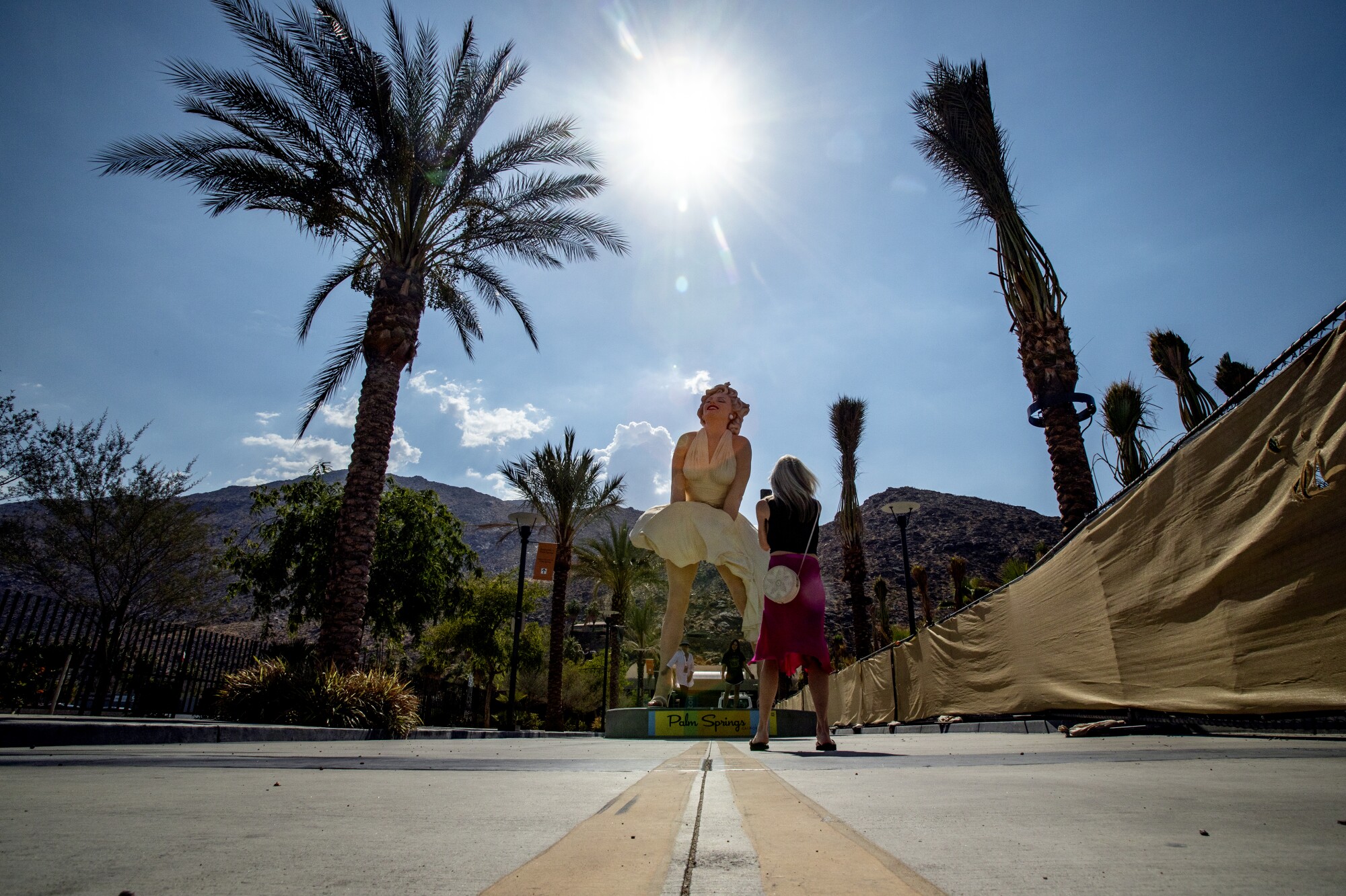 As the sun beats down on the Forever Marilyn statue, tourists stop for quick photos in 110 degree temps in Palm Springs
