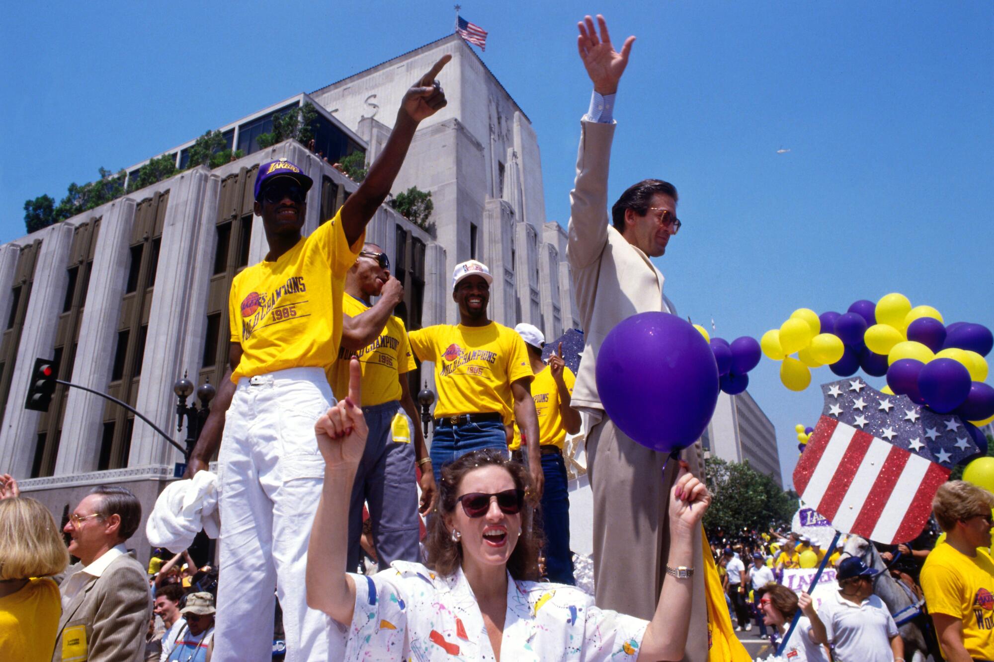 Lakers team members stand on a float as it rolls past The Times' building on 1st Street in downtown.