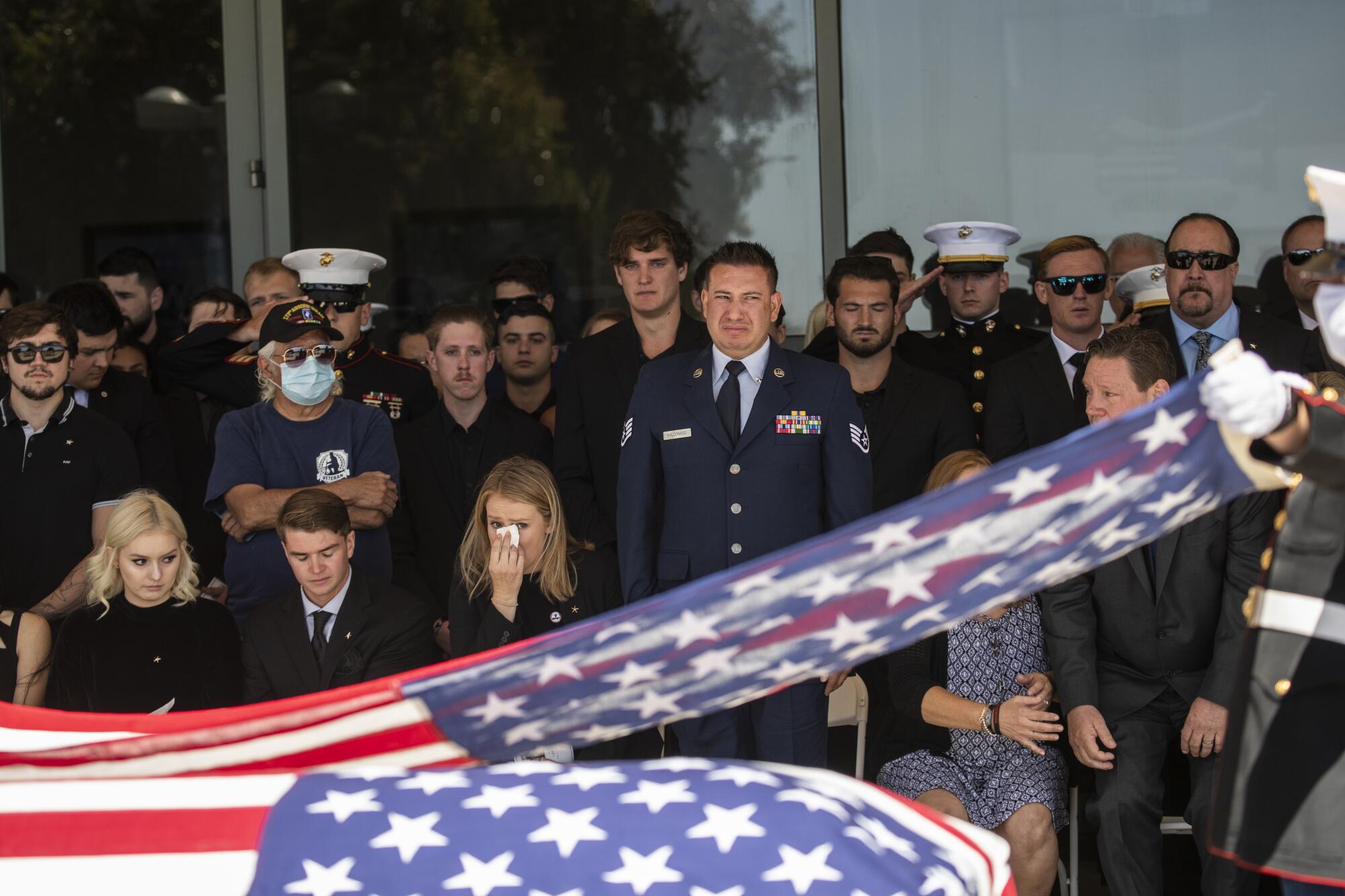 Family members of U.S. Marine Corps. Sgt. Nicole L. Gee gather near a U.S. flag-draped coffin.