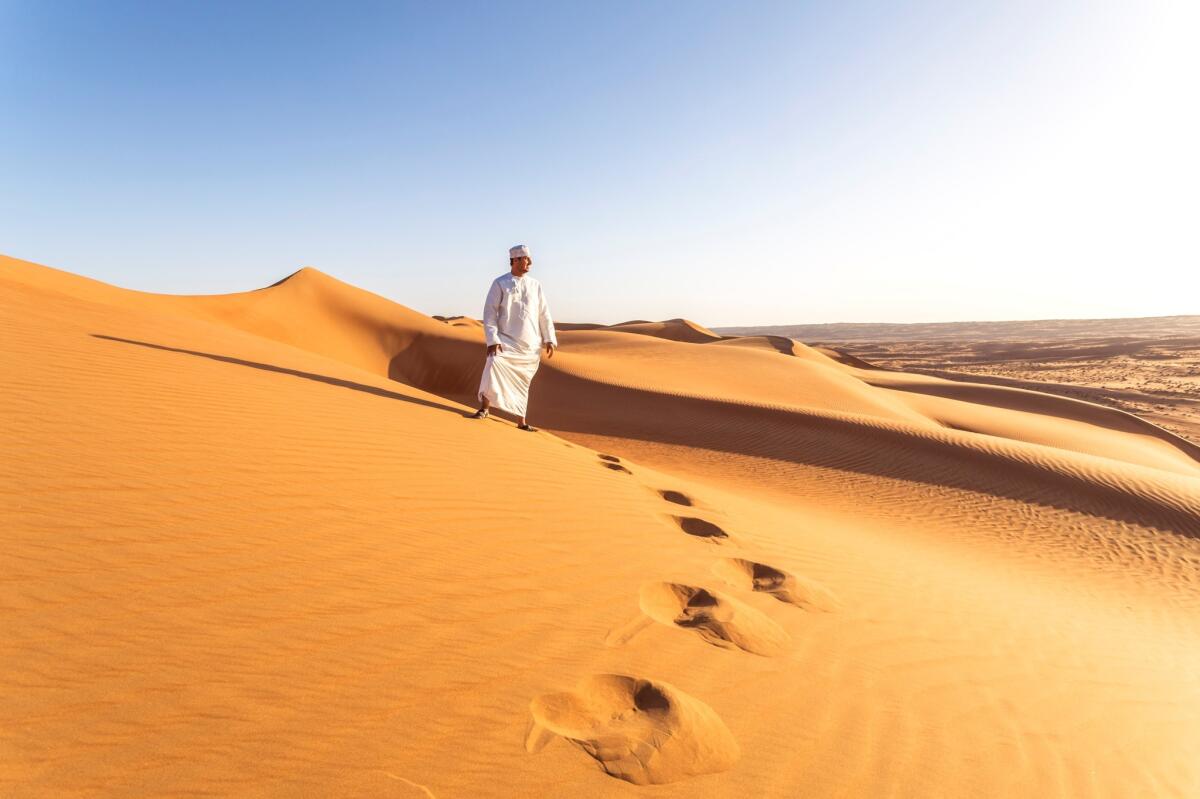 Bedouin on the sand dunes at sunset, Wahiba Sands, Oman.