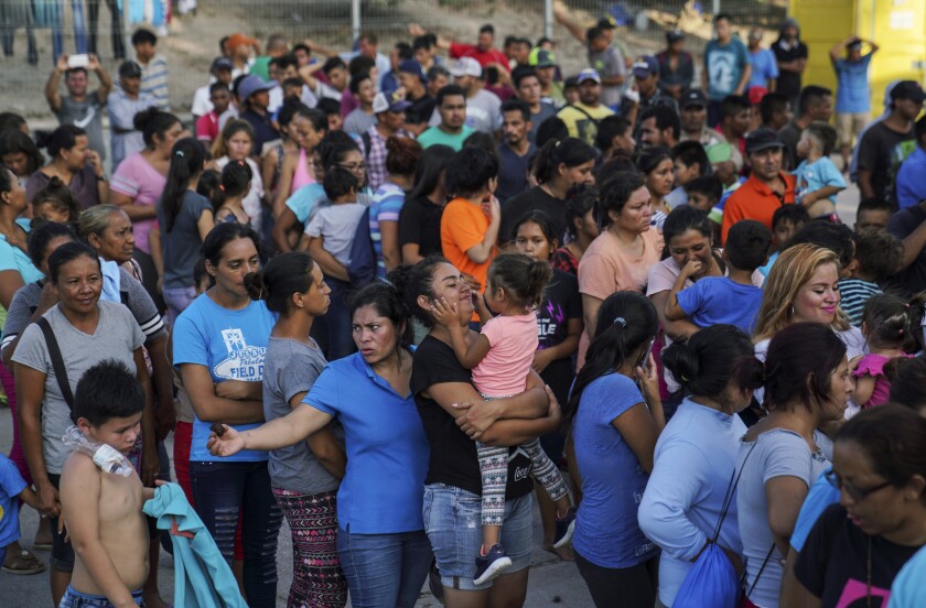 Migrants wait in line to get a meal.