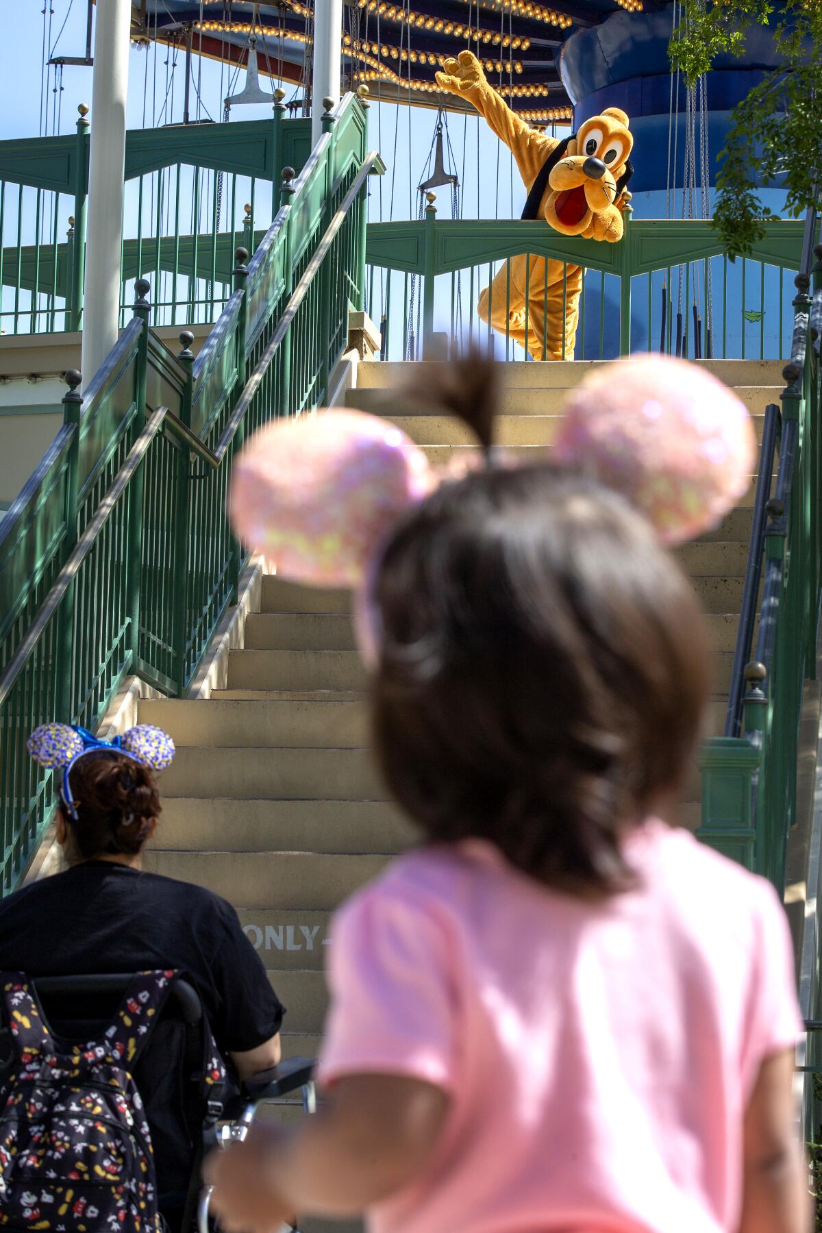 Pluto waves from a great social distance to a young Disney fan. 