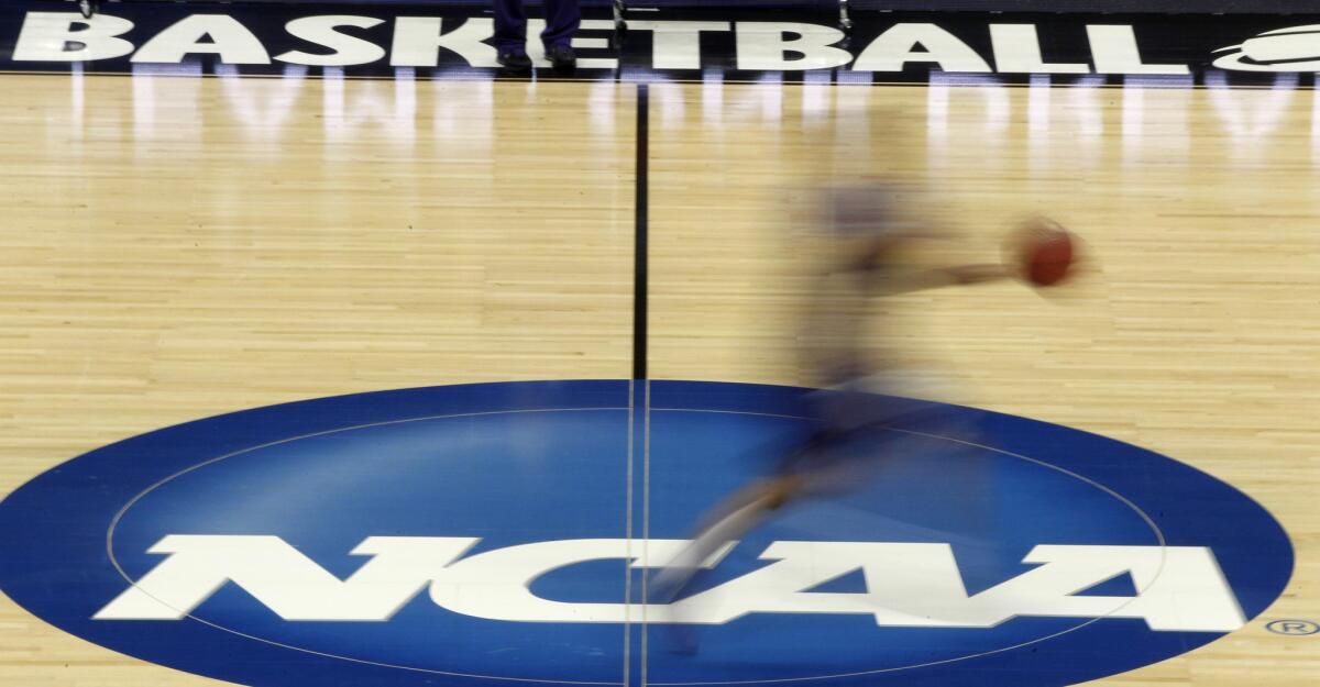 A player runs across the NCAA logo at midcourt during a college basketball tournament practice on Mar. 14, 2012.