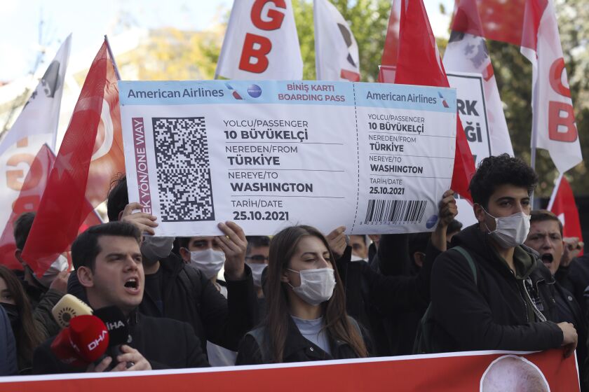 Members of a Turkish group hold a symbolic boarding pass for 10 foreing ambassadors as they stage a protest near the U. S. Embassy to support Turkey's President Recep Tayyip Erdogan, in Ankara, Turkey, Monday, Oct. 25, 2021. Erdogan last Saturday announced he ordered 10 ambassadors, including those from the US, Germany and France, be declared persona non grata, following a joint statement from the envoys calling for the release of Turkish activist Osman Kavala. (AP Photo/Burhan Ozbilici)