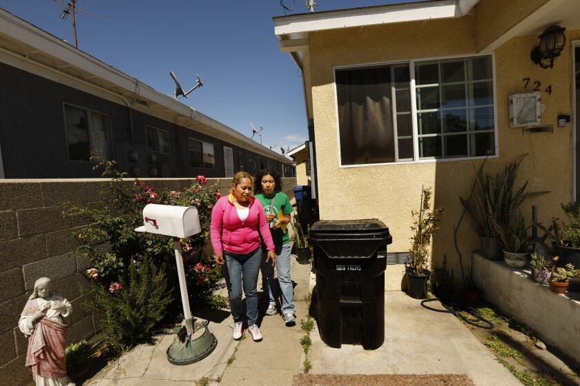 Two women walk outside a home beside a mailbox